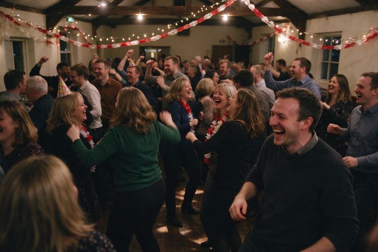 Grande fête de fin d’année, des salariés dansent sous des guirlandes lumineuses dans une salle décorée