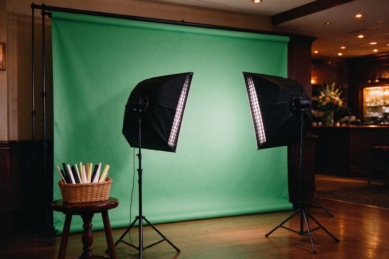 Fond vert prêt à servir, éclairé par deux boîtes à lumière, avec un panier d’accessoires posé devant et personne autour
