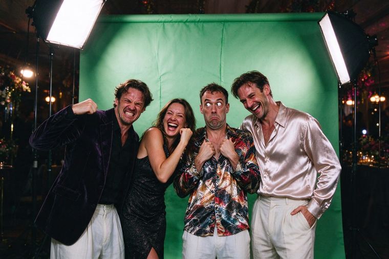 Quatre amis qui font les fous devant un fond vert, grimaces, bras en l’air et grands éclats de rire