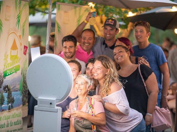 Groupe d’amis souriant devant une borne photo dans un restaurant au bord du lac